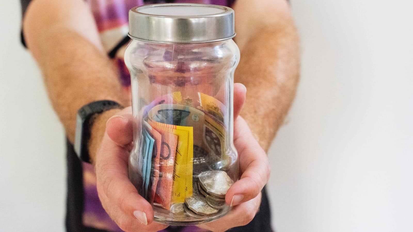 Hand holding a glass jar filled with money